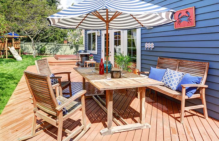 Wooden patio set with striped umbrella on a sunny deck—perfect for relaxing after roofing work.