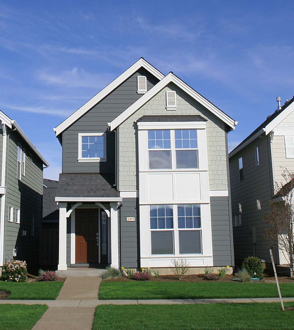 Two-story gray house with white trim, new siding, large windows, and a brown front door.
