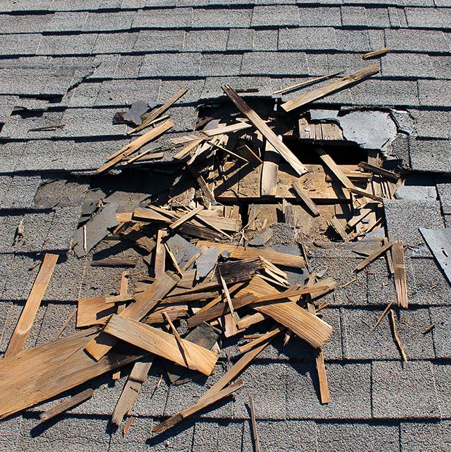 Shingles and wood debris scattered on a damaged roofing deck, serviced by Horizon Exteriors.