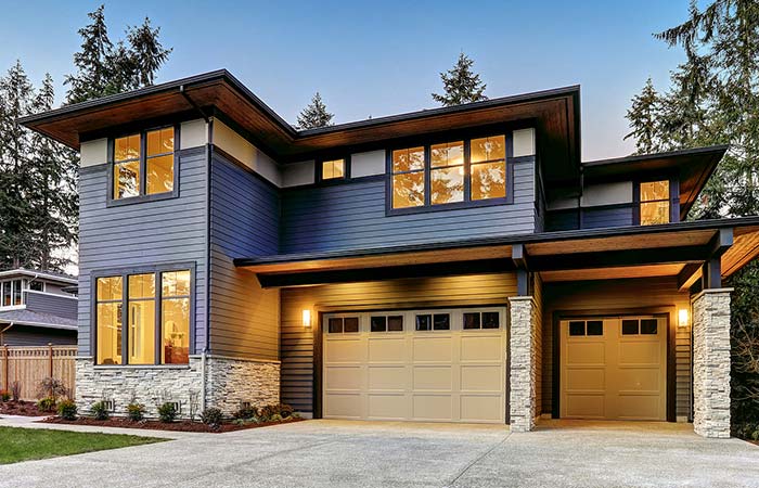 Modern two-story Wisconsin house with large windows, stone, siding, and double garage at dusk.