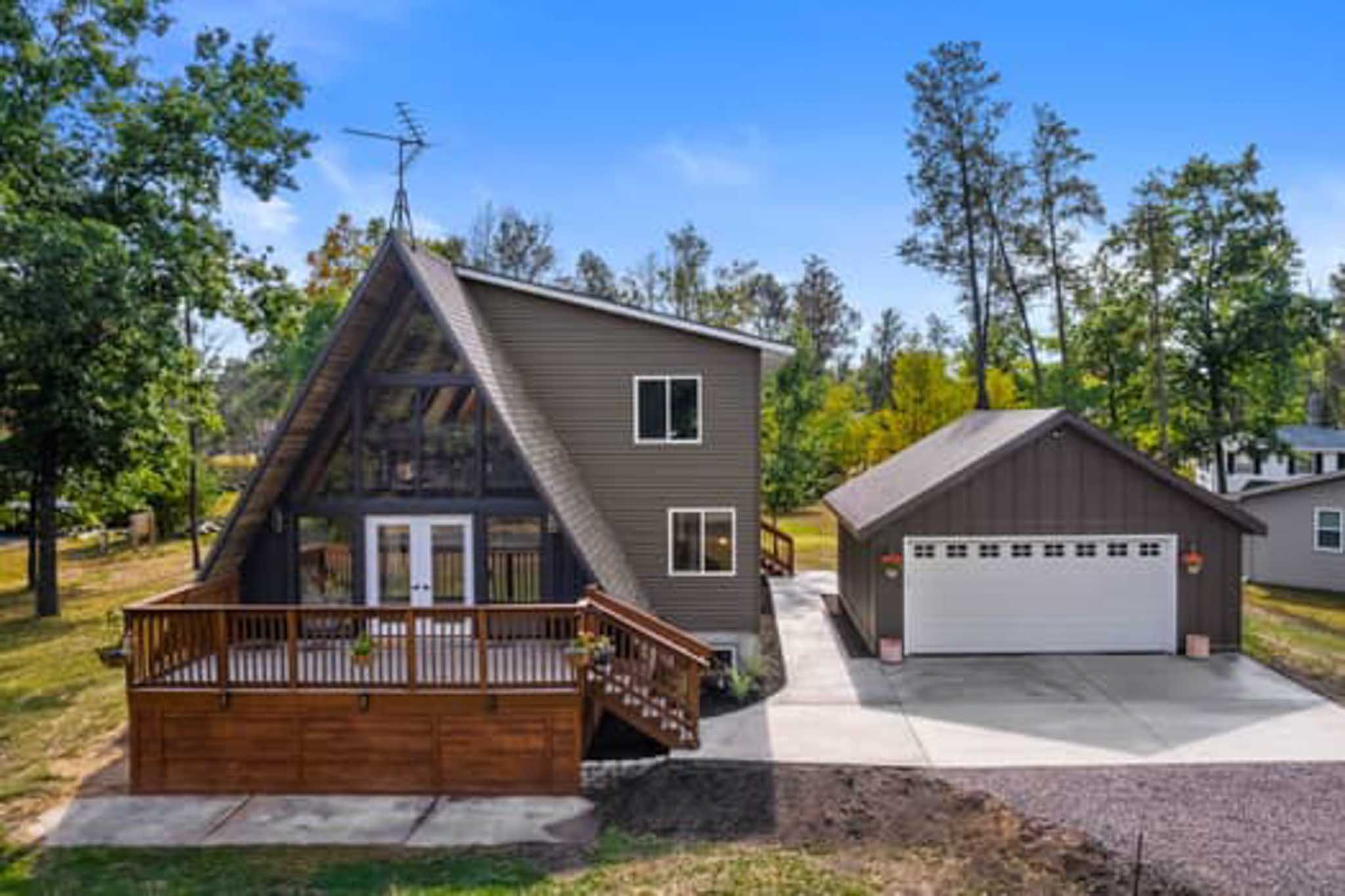 A-frame house with large deck, detached garage, and siding contractor Wisconsin craftsmanship.
