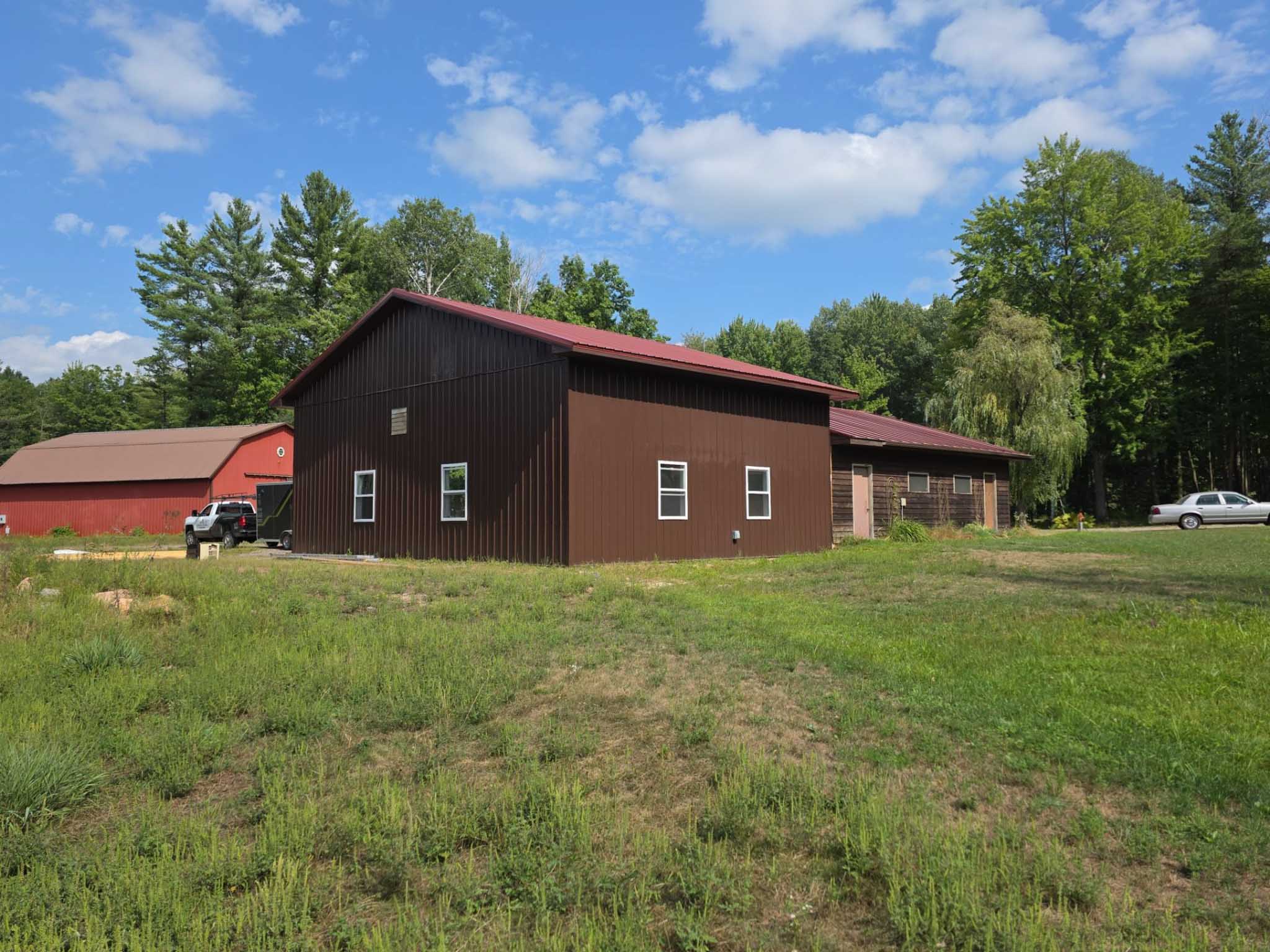 Brown building with red roof in grassy yard, built by a trusted siding contractor in Wisconsin.