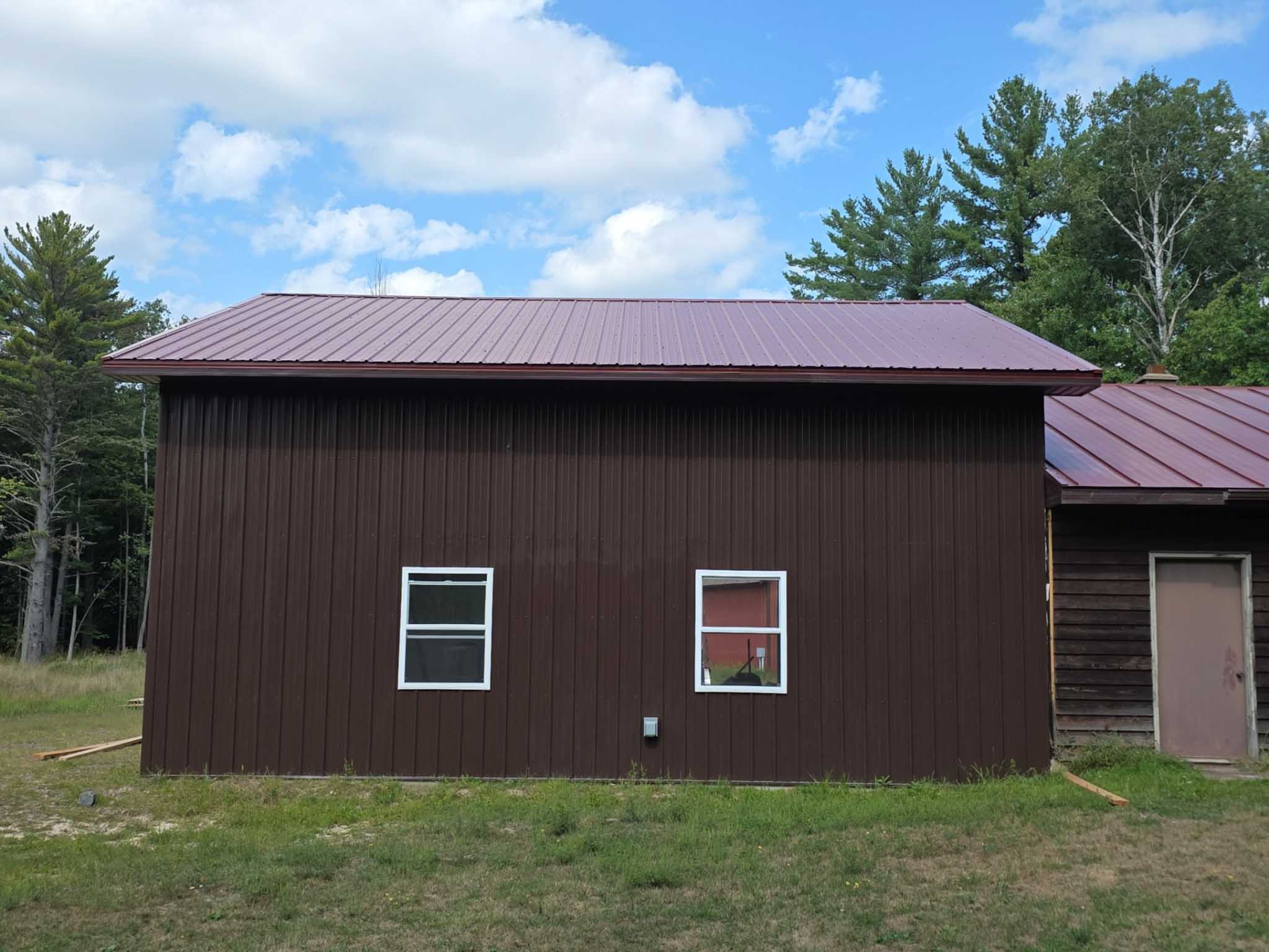 Brown building with two white windows and a door, crafted by a siding contractor in Wisconsin.
