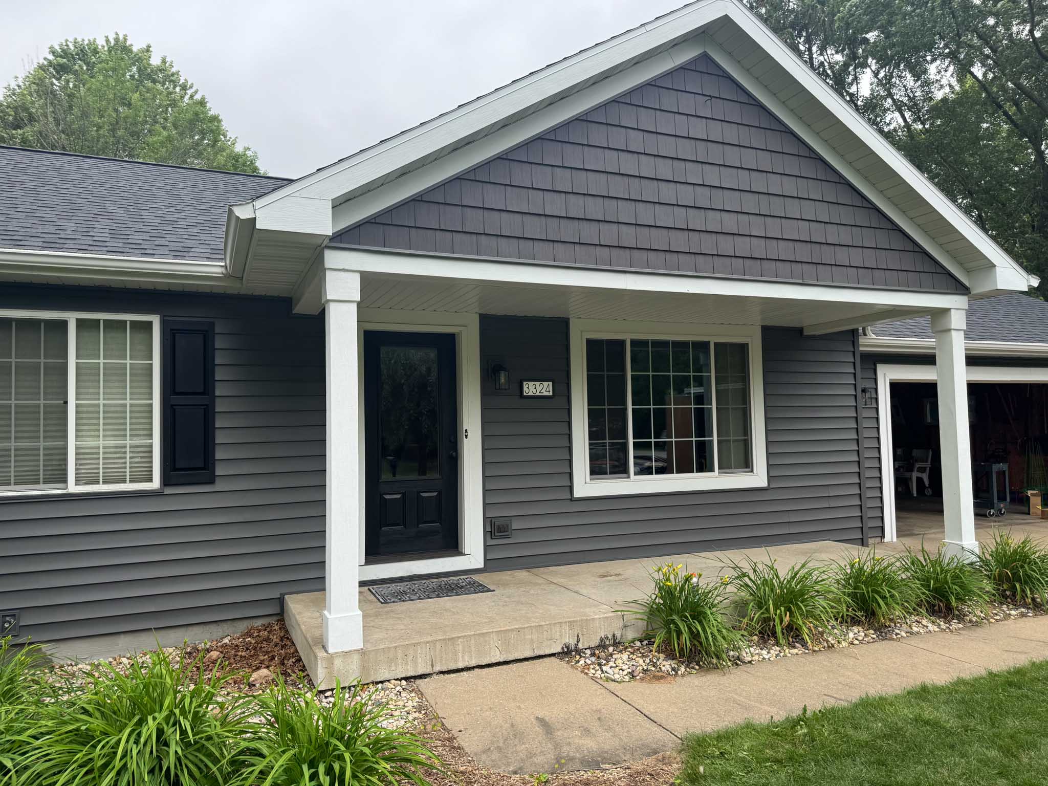 Gray house with white trim, black door, porch—built by a Wisconsin siding contractor.