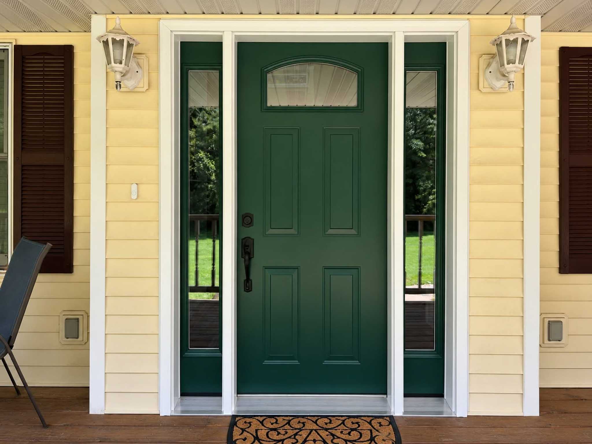 A green front door with side windows on a yellow house featuring Replacement Windows Wisconsin.