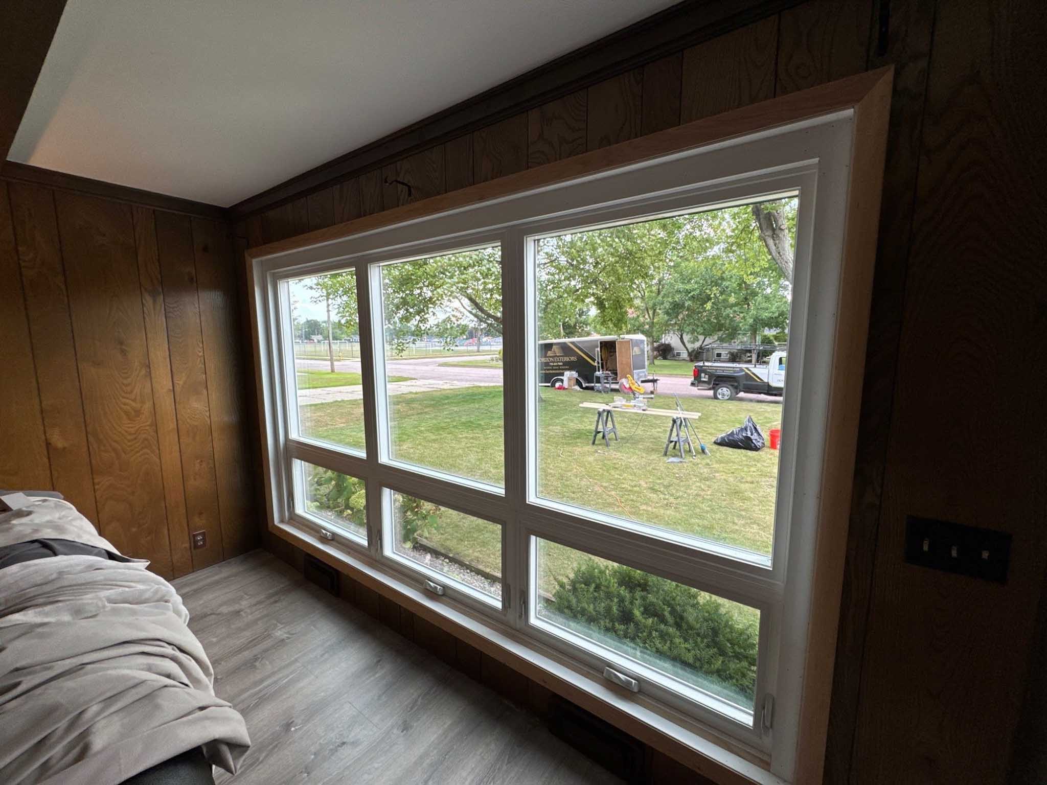 Large window with six panels, Replacement Windows Wisconsin views a grassy yard on a cloudy day.