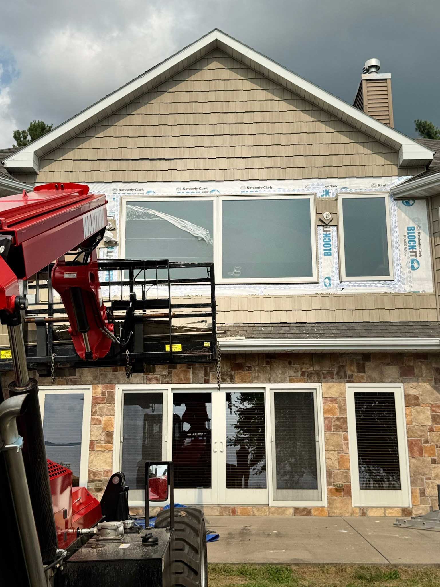Workers install large replacement windows on a house’s second floor using lifts in Wisconsin.